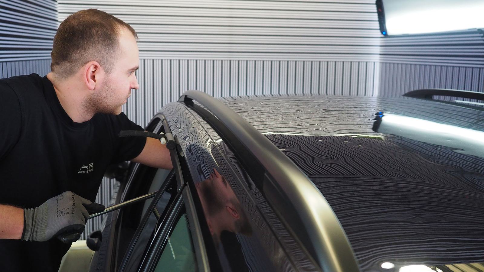A PDR-Team technician working a hail-dented roof under the light bar